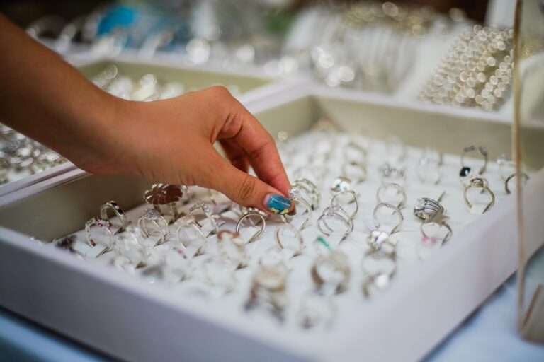 Hand bei der Auswahl eines Rings aus einer Schmuckauslage